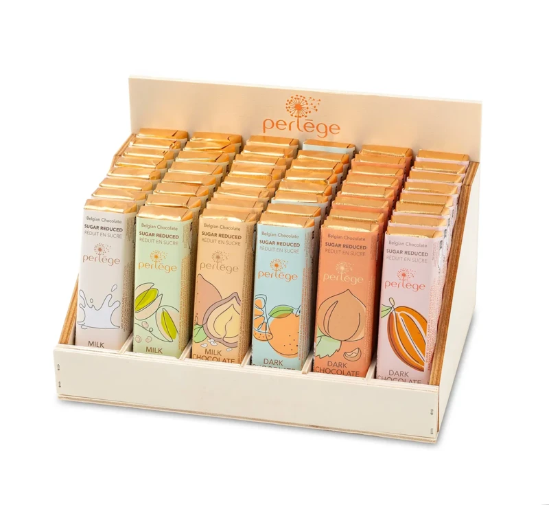 Présentoir en bois clair marqué « perlège », garni de plusieurs rangées de bâtons de chocolat Belgian Chocolate aux emballages colorés variés, gamme réduite en sucre.