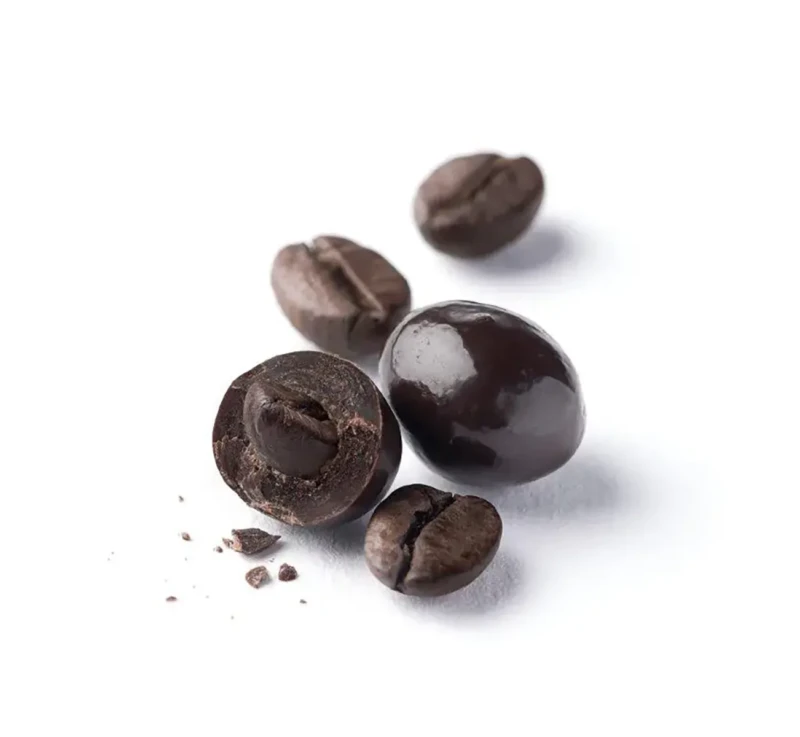 Grains de café Santos enrobés de chocolat noir Café-Tassé, présentés sans emballage sur fond blanc, l'un croqué laissant voir le grain de café.