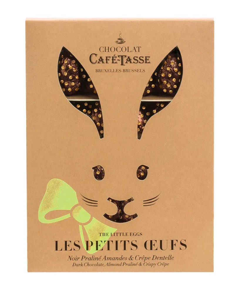 Boîte kraft Café-Tassé découpée en forme d'oreilles de lapin, laissant apparaître des œufs en chocolat emballés dans un papier alu marron à pois dorés.