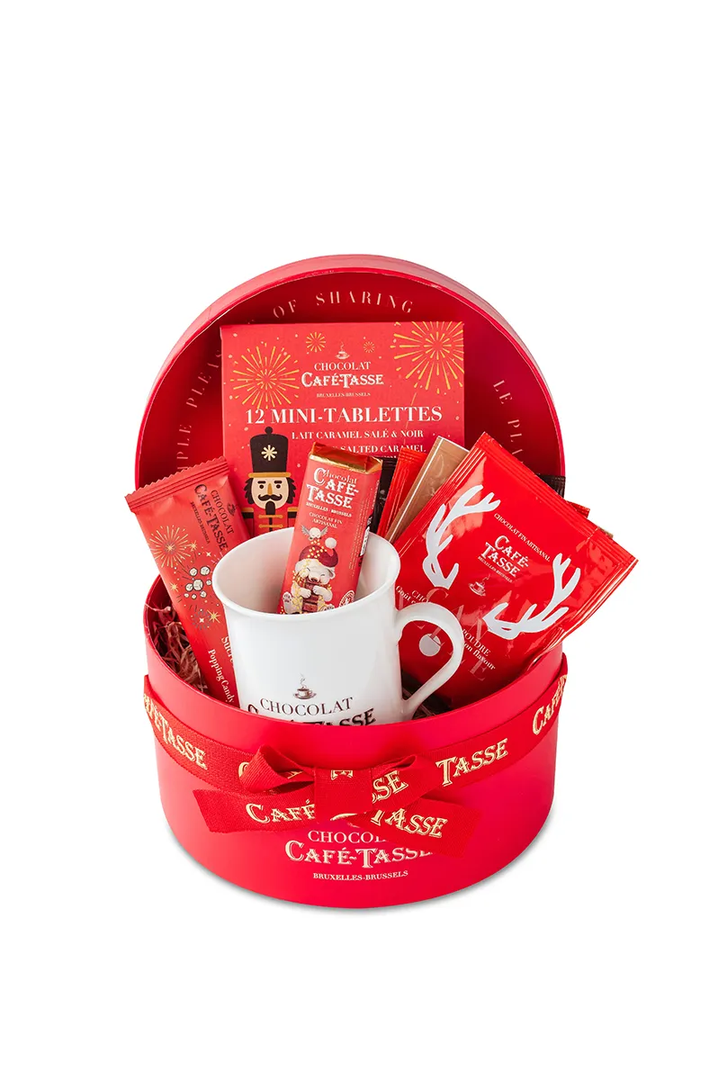 Corbeille ronde rouge de Noël nouée d'un ruban « Café-Tassé », garnie d'un mug blanc, d'une boîte « 12 Mini-Tablettes Lait Caramel Salé & Noir » et de sachets illustrés de bois de renne.