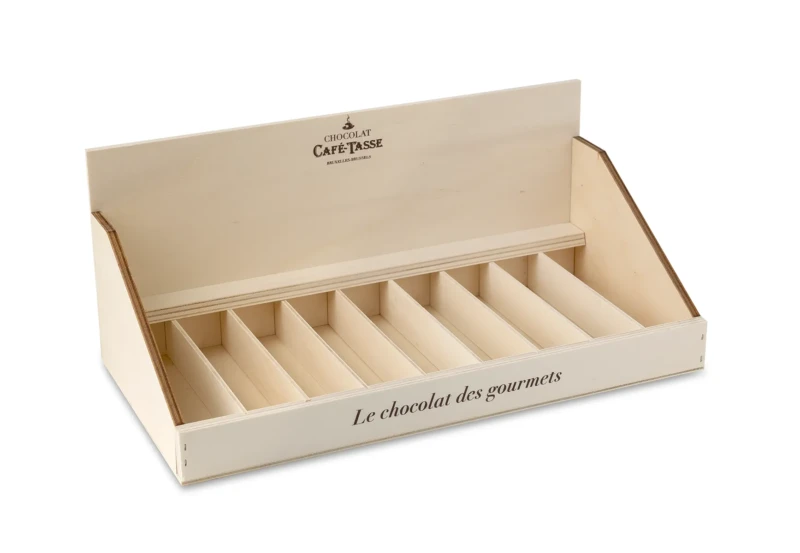 Présentoir en bois clair à neuf compartiments inclinés, vide, gravé du logo « Chocolat Café-Tassé Bruxelles-Brussels » et de la mention « Le chocolat des gourmets ».