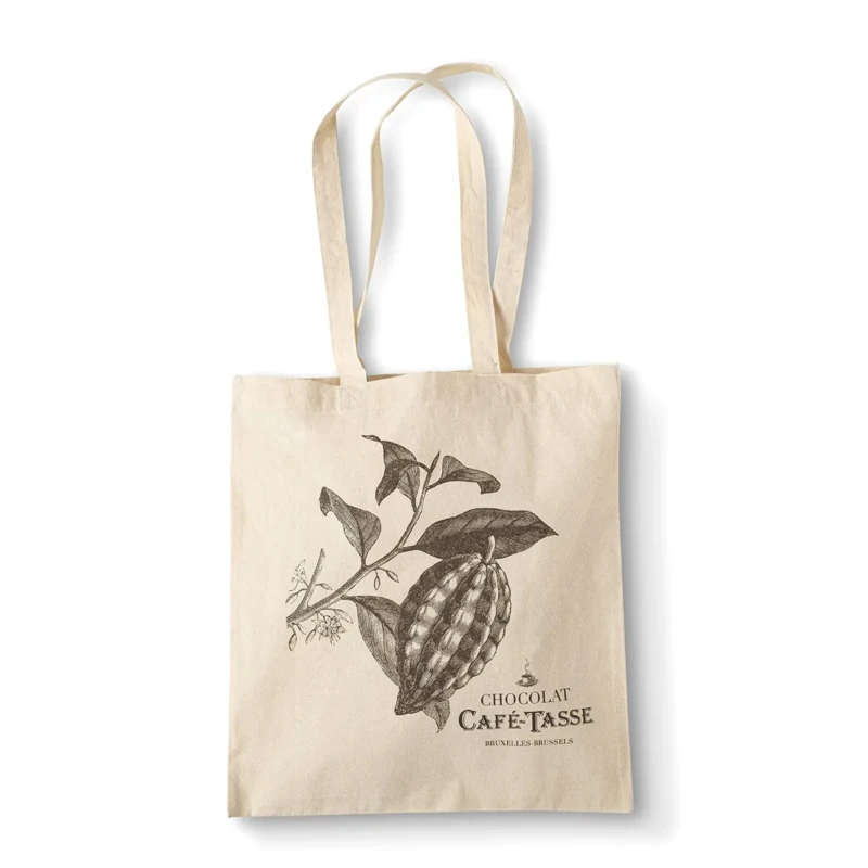Tote bag en toile beige illustré d'une branche de cacaoyer avec cabosse et feuilles, mention « Chocolat Café-Tassé Bruxelles-Brussels », posé à plat sur fond blanc.