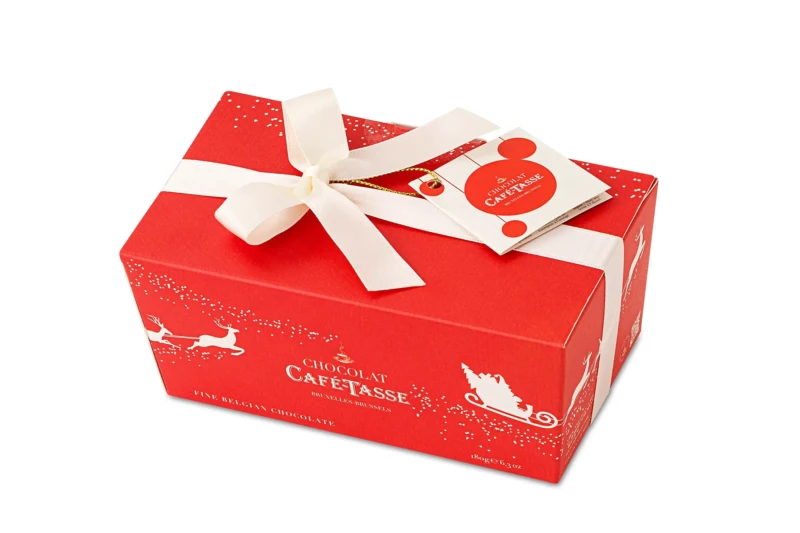 Ballotin cadeau rouge de Noël noué d'un ruban blanc, étiquette ronde « Chocolat Café-Tassé », illustration dorée d'un traîneau tiré par des rennes, mention « Fine Belgian Chocolate ».